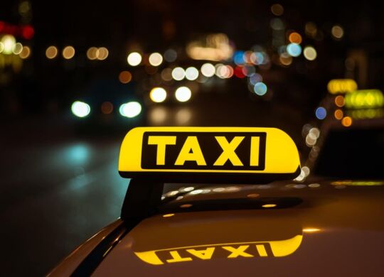 yellow-black-sign-taxi-placed-top-car-night_181624-10624